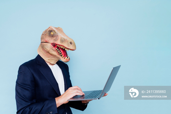 Man in dinosaur mask using laptop.