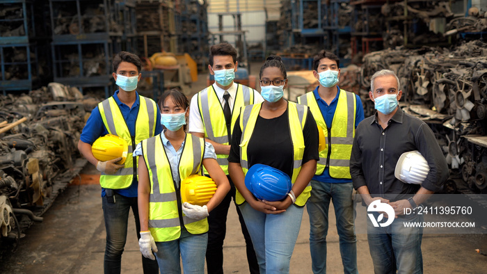 group of diversity Workers wear protective face mask holding hard hat Stand in mourning  together in warehouse industrial factory  during Coronavirus or COVID-19 pandemic. health care in industry