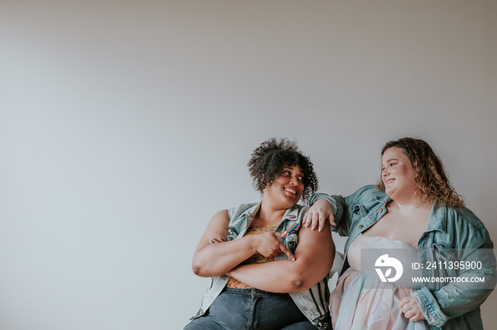 portrait of 2 plus size friends looking at each other