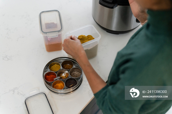 Woman putting spices into container