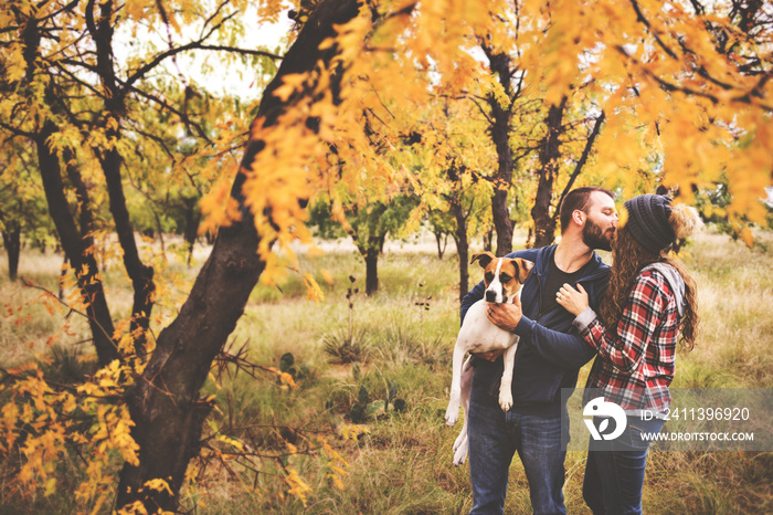 Cute couple playing with their dog in the fall leaves