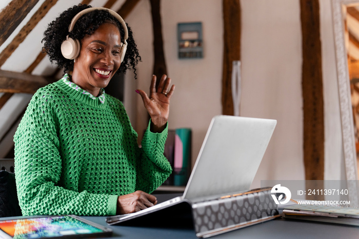 Smiling businesswoman waving during video call in office