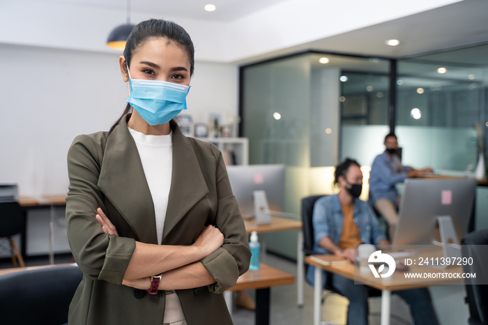 Asian young businesswoman wearing mask working on computer in office.