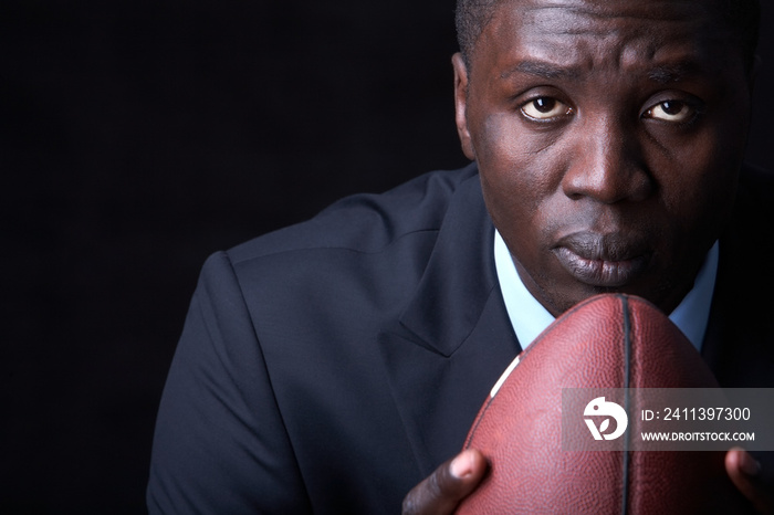 Serious businessman with rugby ball looking at camera