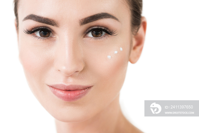 Happy young woman using facial cosmetics