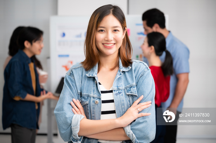 Confidence team leader. Young women asian owner startup business looking camera with smile while his colleagues working in the background