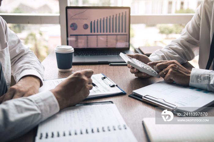 Two business people talking about report graph and analysis about finance budget or cost company and using calculator in office room.