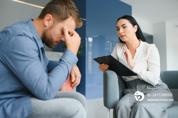 psychology, mental therapy and people concept - woman psychologist talking to sad young man patient at psychotherapy session.