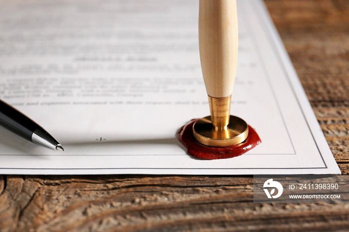 Document with notary public wax seal on table, closeup