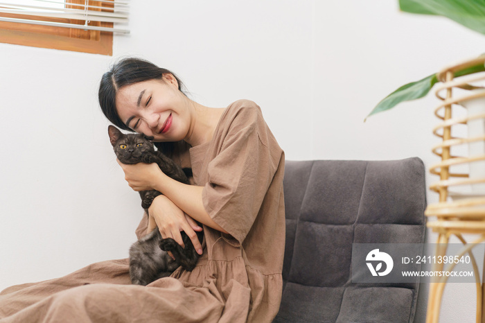 Pet lover concept, Young Asian woman sitting to relax on sofa on floor to playing and hugging cat