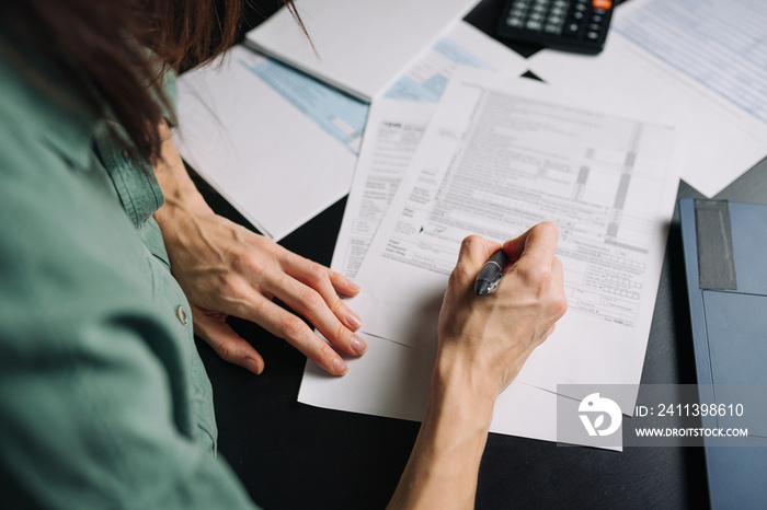 Woman filling US tax form 1040. tax form us business income office hand fill concept. Closeup