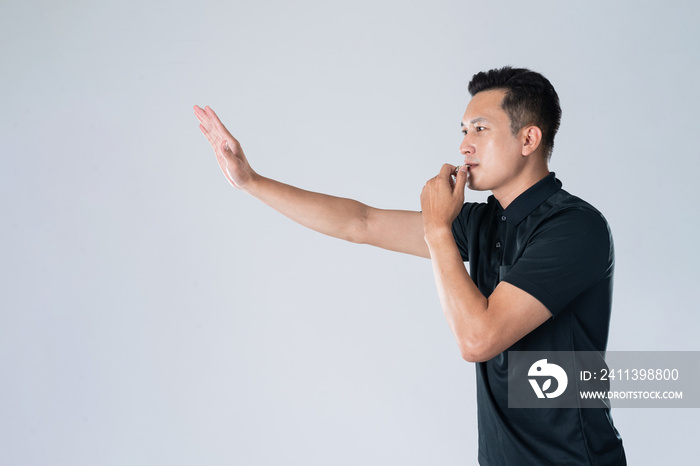 Football referee holding whistle and pointing with isolated hand.