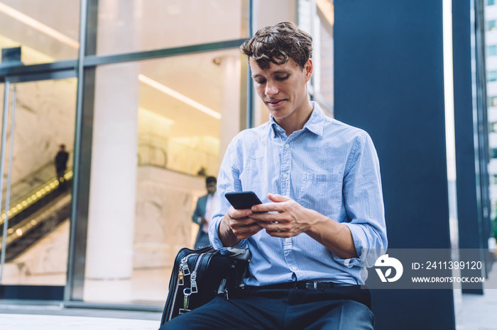 Handsome male professional trader using cellphone for checking financial information on website using 4g for browsing with cellular, Caucasian businessman in downtown typing text for send sms