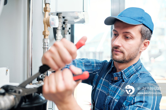 Contemporary young mechanic from household maintenance service repairing pipe