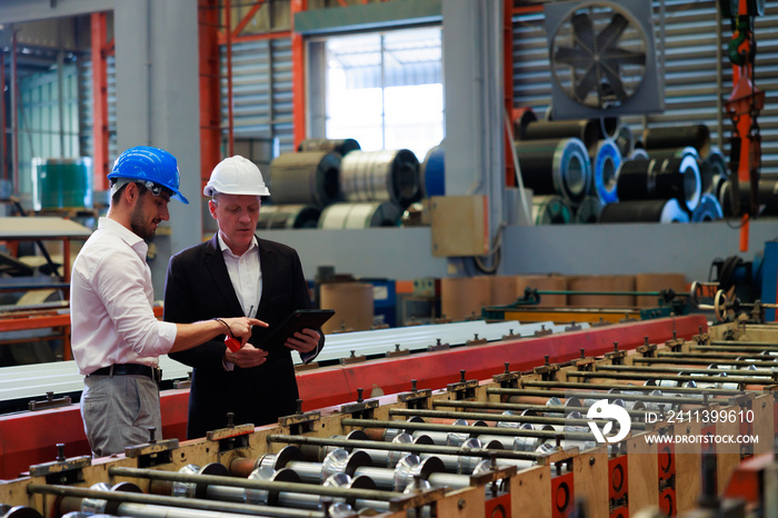 Caucasian business man and Factory engineer talking and discussion at Heavy Industry Manufacturing Factory. worker in safety hardhat at factory industrial facilities