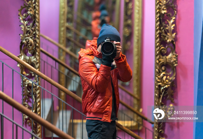 Portrait of focused young male Stylized photographer looking through camera on the mirror, looking glass.  Stylized photographer with professional camera.
