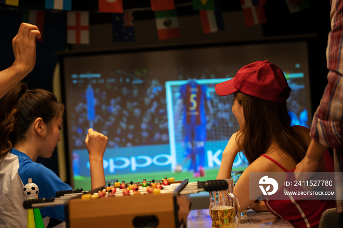 年轻朋友一起从投影屏幕上看足球比赛