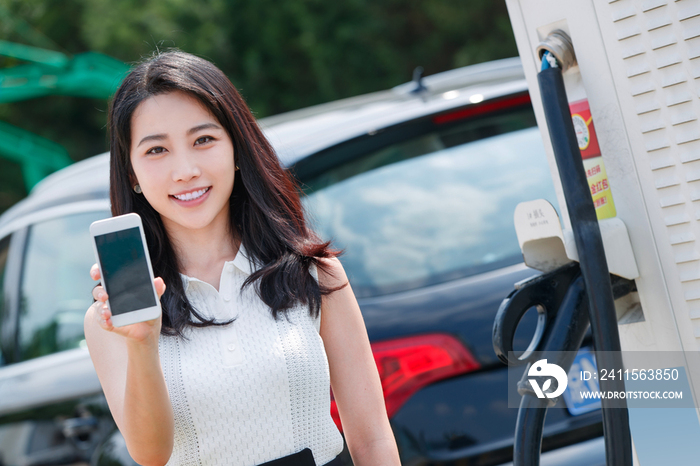 青年女人使用手机自助充电汽车