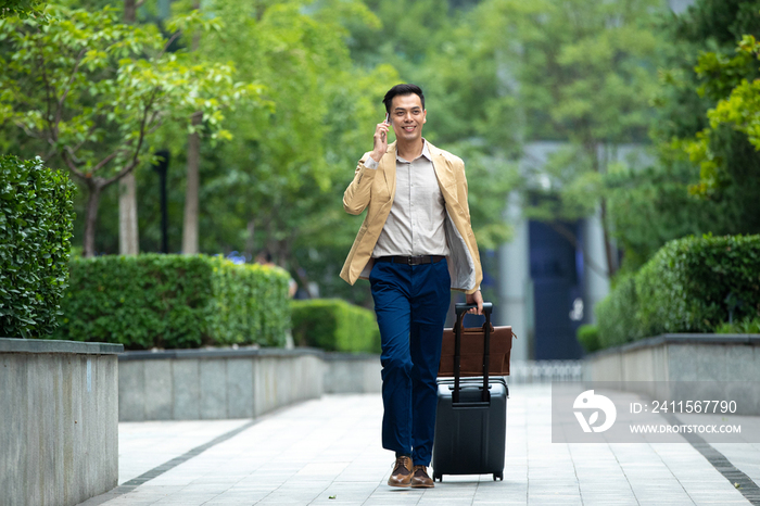 户外拉着行李打电话的商务男子