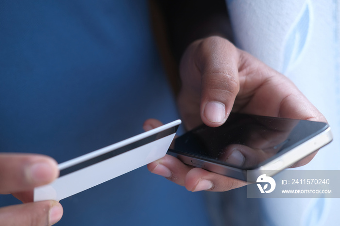 Mans hands holding a credit card using smart phone for online shopping