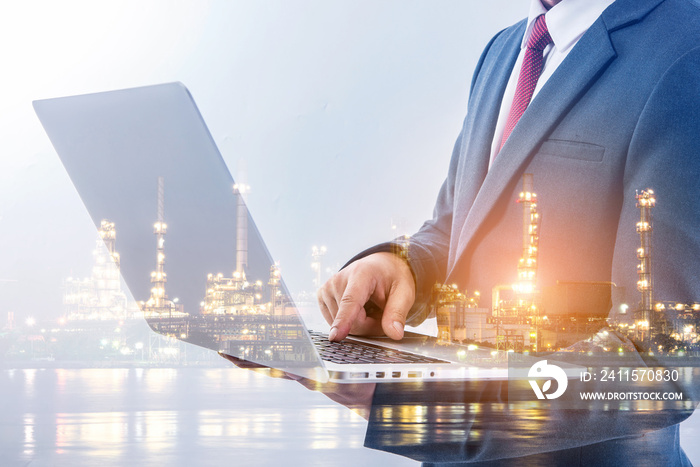 Double exposure of businessman using laptop with refinery plant background