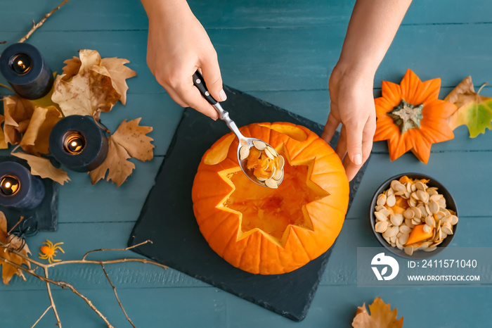 Woman carving pumpkin for Halloween at table