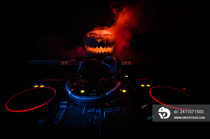 Halloween pumpkin on a dj table with headphones on dark background with copy space. Happy Halloween 