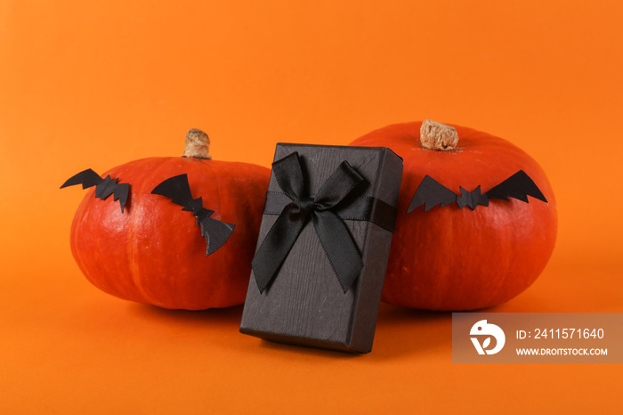 Happy halloween celebration. Pumpkins with bats and black gift box on orange background