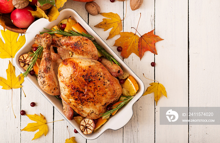 Roasted turkey garnished with cranberries on a rustic style table decorated with pumpkins, orange, a