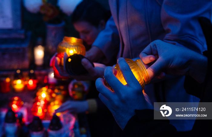 People light candles to put it on a tombstone - all souls day preparing in the cemetery - blue hour 