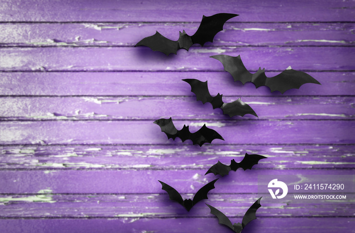 halloween, decoration and scary concept - black bats flying over ultra violet shabby boards backgrou