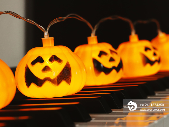 Electric string Halloween pumpkin lights on piano keyboard for Halloween party.