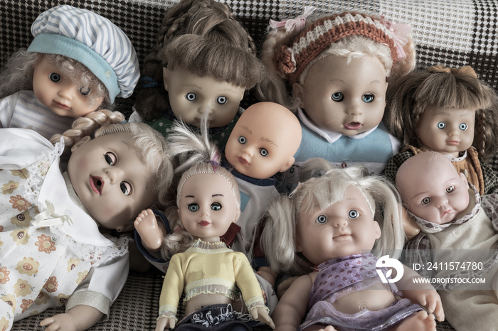 A group of creepy dolls sitting on the couch