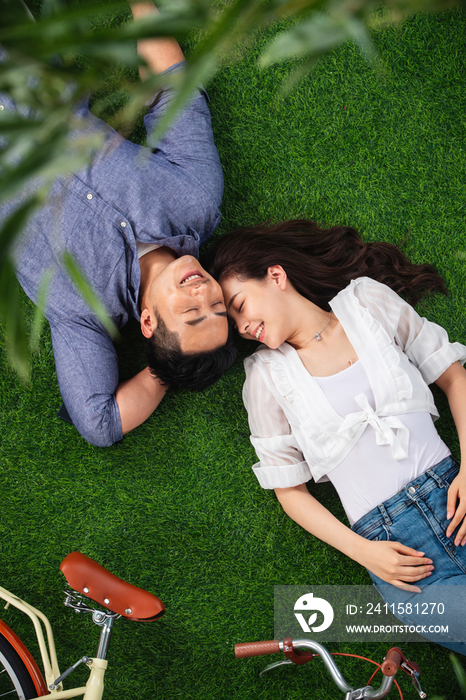 幸福的青年伴侣躺在草地上享受亲密时光