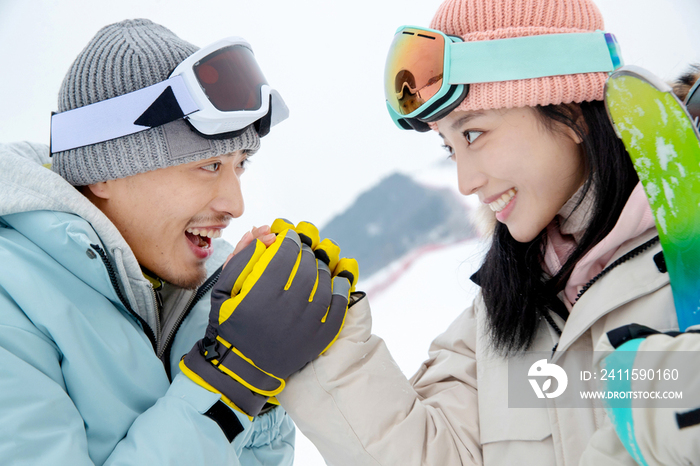 滑雪场上青年男人给女朋友捂手