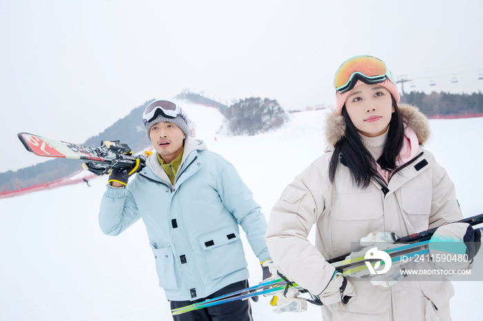 雪场上拿着滑雪板去滑雪的情侣