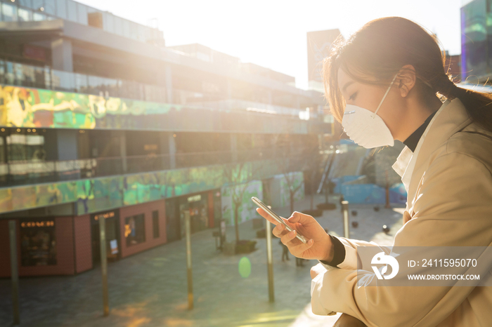 戴口罩的青年女人看手机