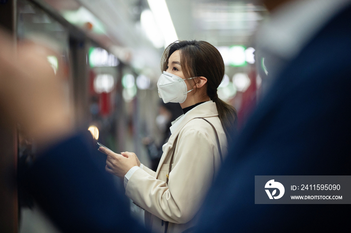 戴口罩的年轻女人站在地铁站台上