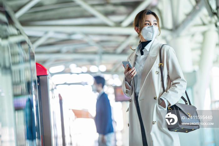 戴口罩的年轻女人站在地铁站台上