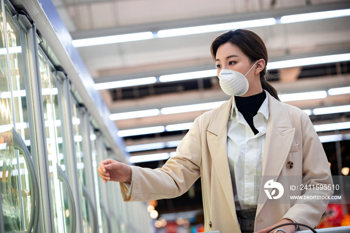 戴口罩的青年女人在超市购物