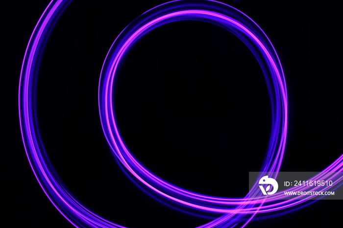 Long exposure photograph of neon purple streaks of light in an abstract swirl, parallel lines patter