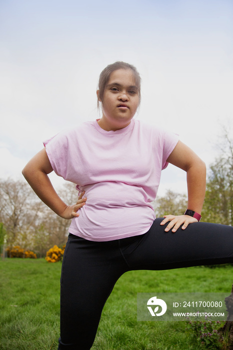 Young curvy girl with Down Syndrome posing in workout clothes in the park