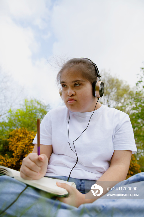 Young mid-sized woman with Down Syndrome listening to music in the park