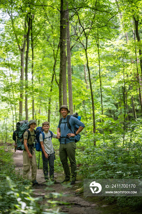 Air Force service member heads out on a hike with his sons on  a backpacking trip.