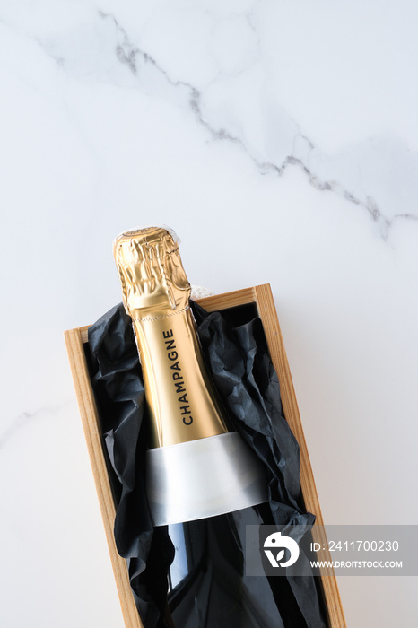 A champagne bottle and a gift box on marble