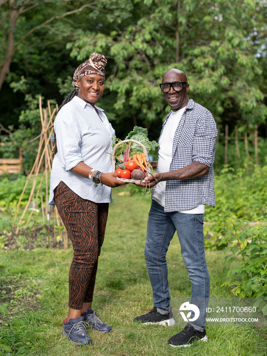 Portrait of mature couple holding vegetables from garden