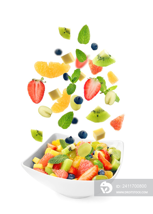 Sliced fruits falling into bowl with salad on white background