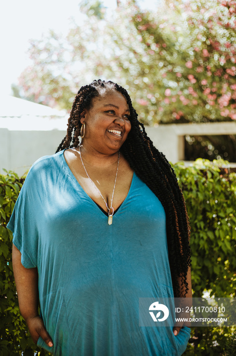 plus size Afro Latinx Haitian American woman smiling under flowering tree looking at camera