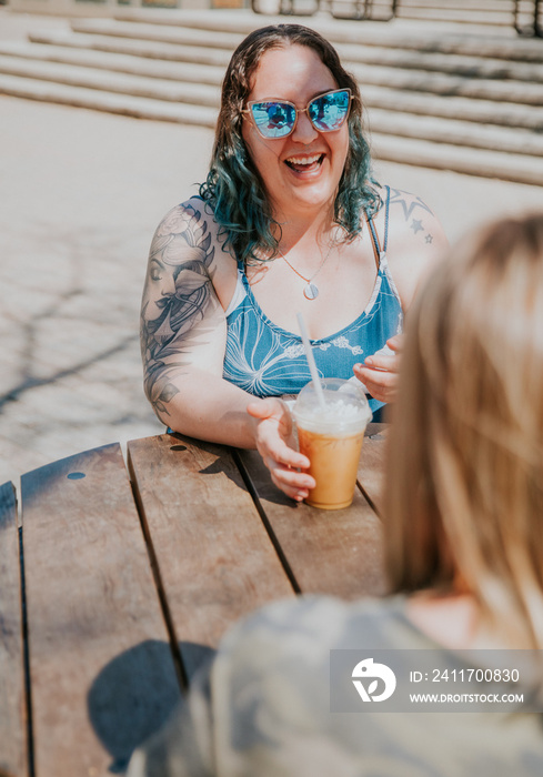 2 friends talk at table and laugh