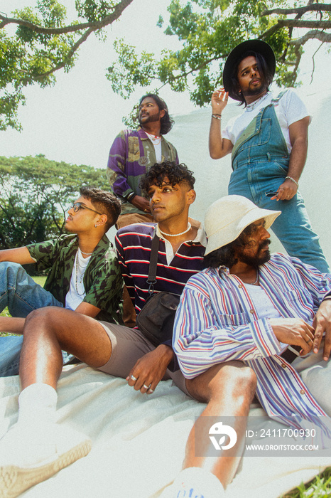 Malaysian Indian men posing and laughing together in a group setting, outdoors, in a park against a cloth backdrop